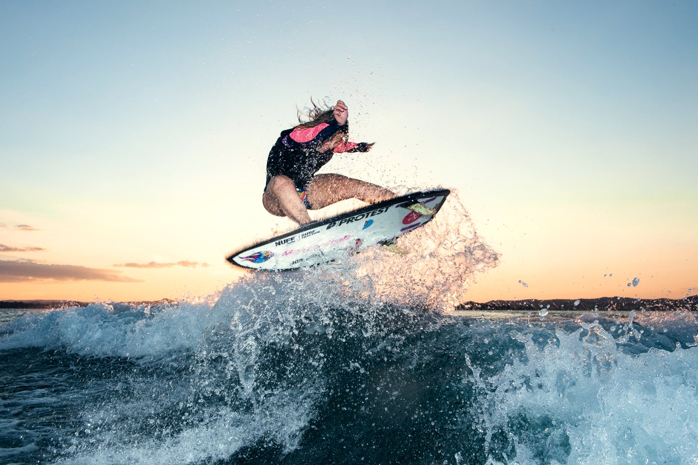 Wake surfer launching off the wave at sunset